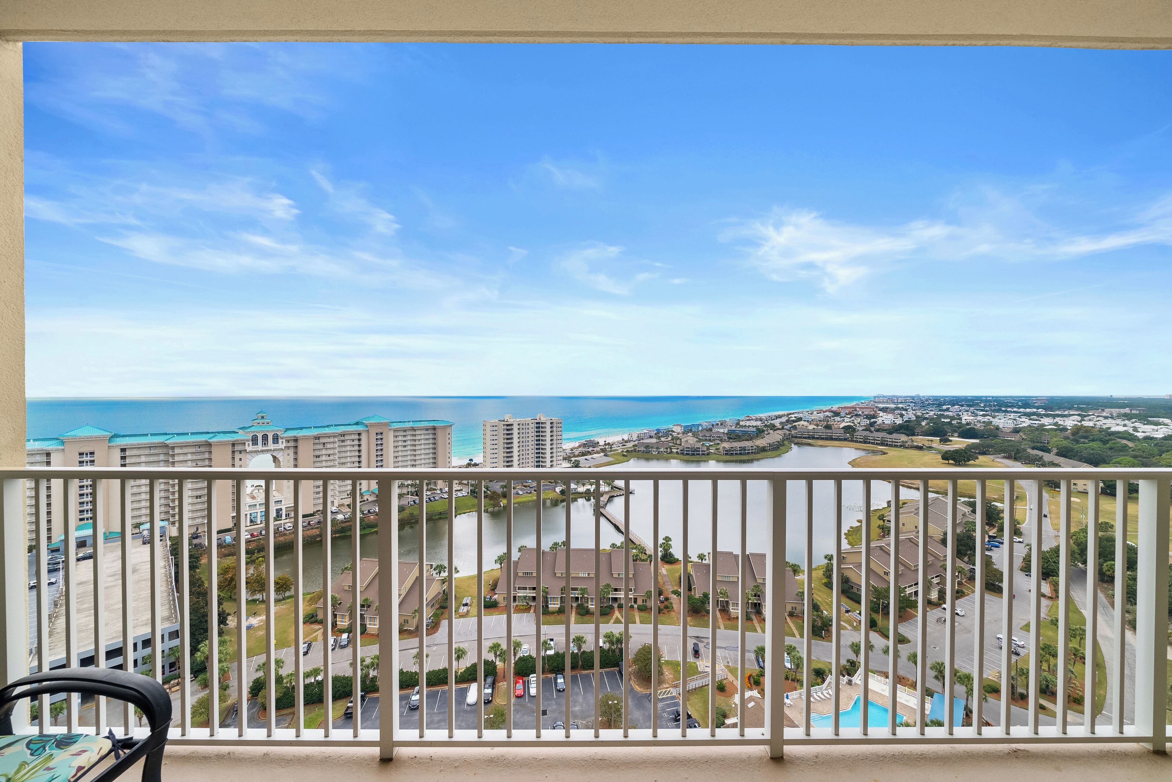 A balcony with a view of a coastal cityscape, including buildings and a body of water.