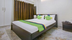 Een hotelkamer met een bed, een nachtkastje, een gordijn en een wandairconditioner.