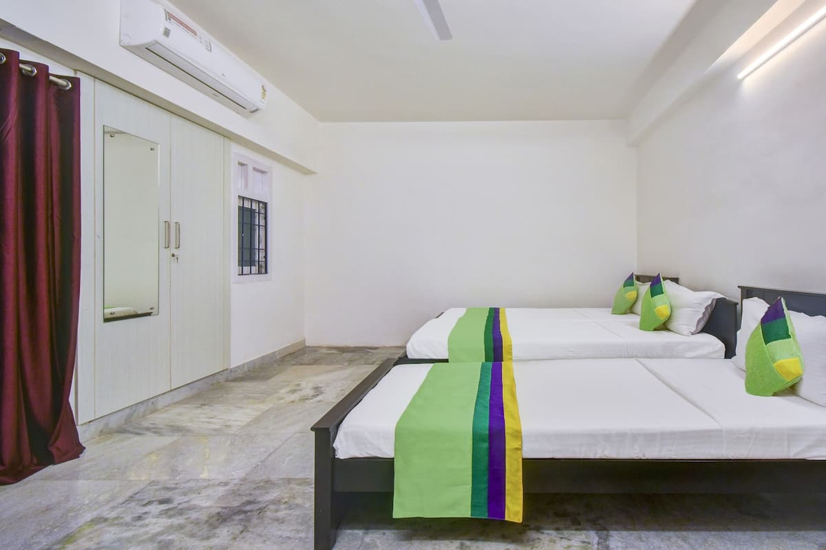 Habitación de hotel con dos camas, un armario, un espejo y un aire acondicionado.