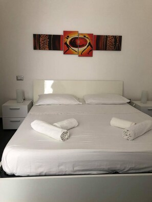 Ein Hotelzimmer mit einem großen Bett, zwei Nachttischen und einem an der Wand hängenden Kunstwerk.