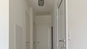 A narrow hallway with wooden flooring, white walls, and a ceiling light fixture.