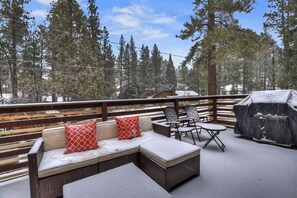 An outdoor seating area with a sofa, chairs, and a grill, surrounded by snow-covered trees. - Welcome to Bearadise by Destination Big Bear : Mountain Retreat in Lower Moonridge! Foosball! Walk to the Zoo & Golf Course! (Big Bear Lake)