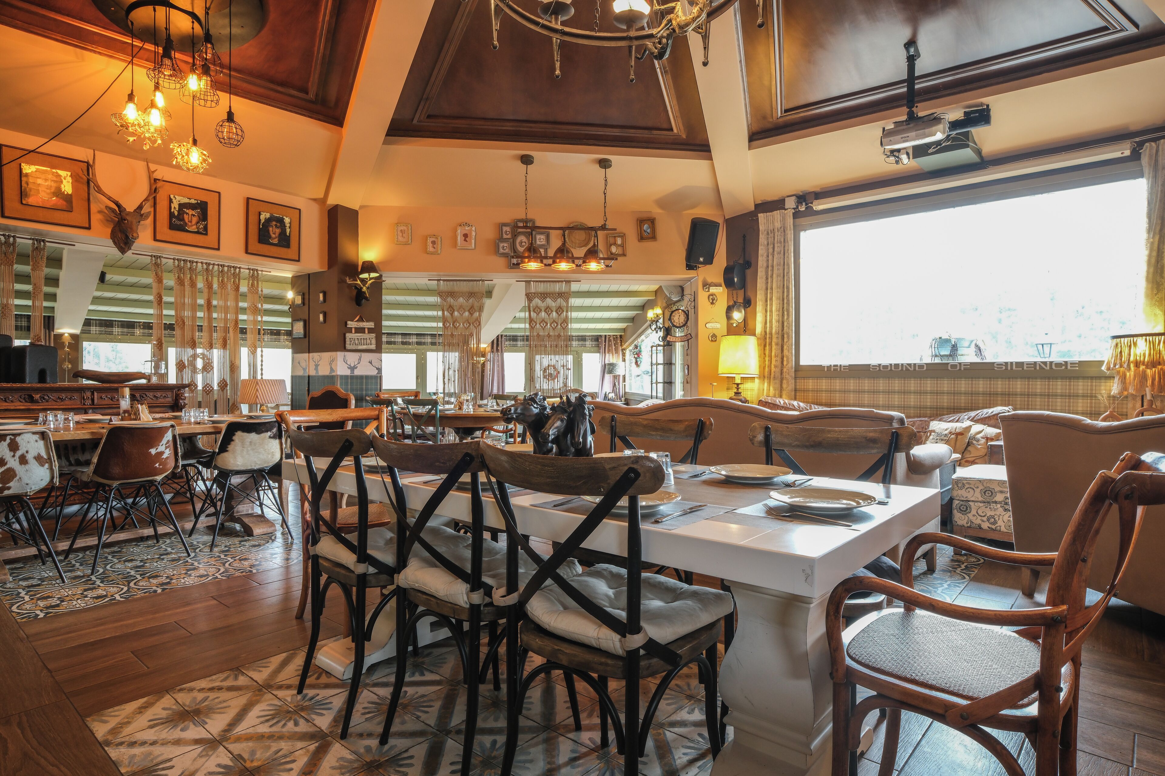 A spacious dining area with a large island, wooden chairs, and a view of the city through large windows.