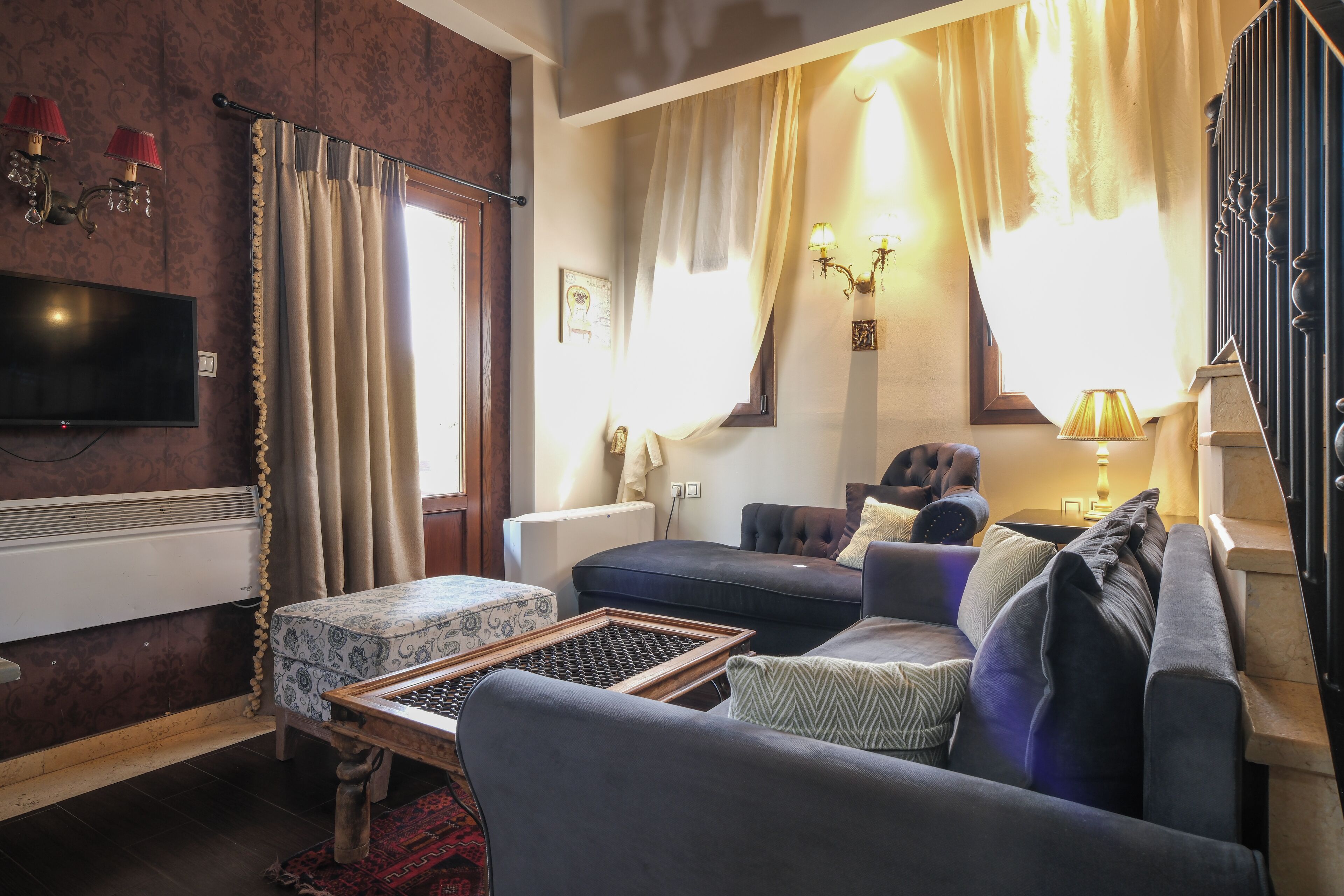 A living room with a sofa, a small table, a TV, and a window with curtains.