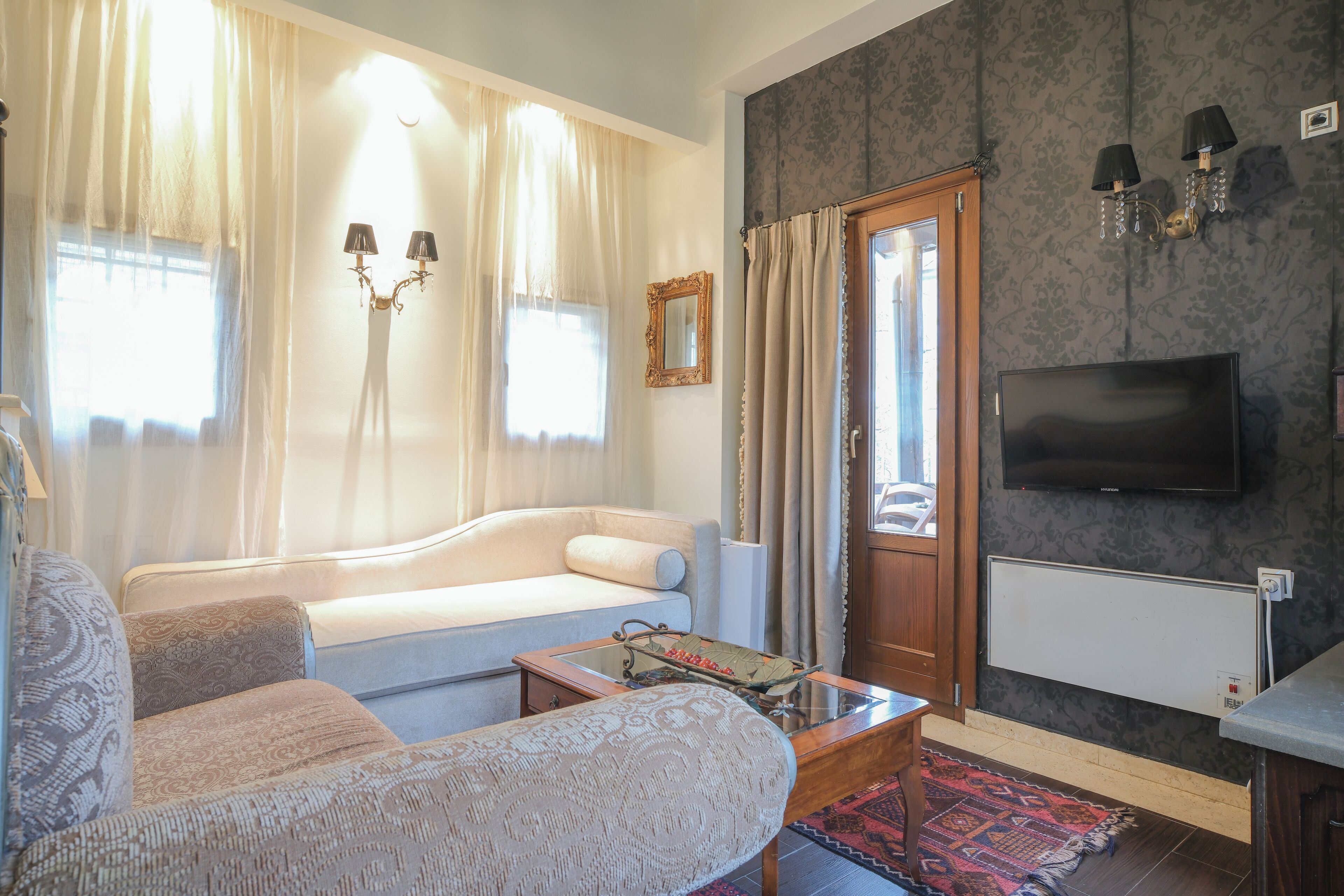 A living room with a sofa, armchairs, a coffee table, a TV, and a patterned rug.