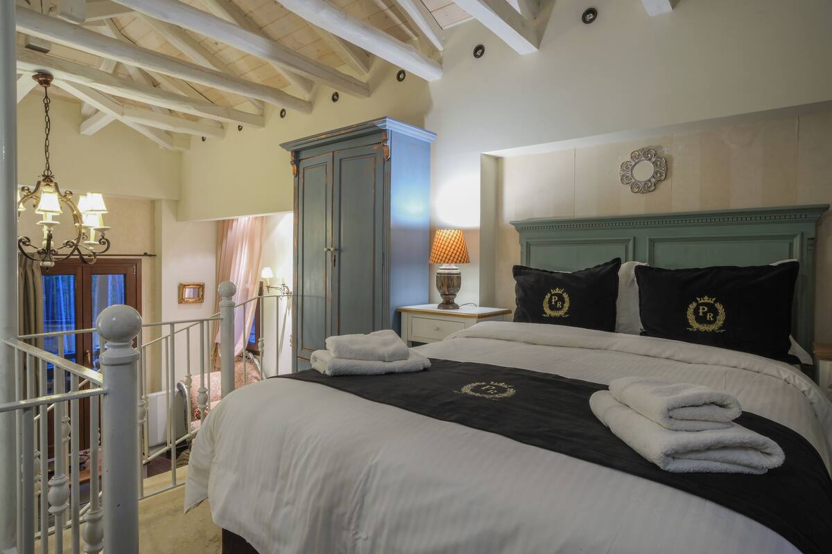 A bedroom with a large bed, a wardrobe, and a chandelier.