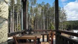 Una terraza de madera con una mesa y sillas, con vista a un bosque.
