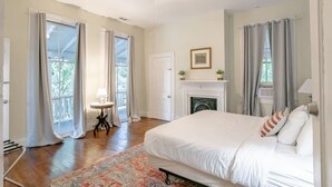 A spacious bedroom with a large bed, a fireplace, and a balcony with curtains.