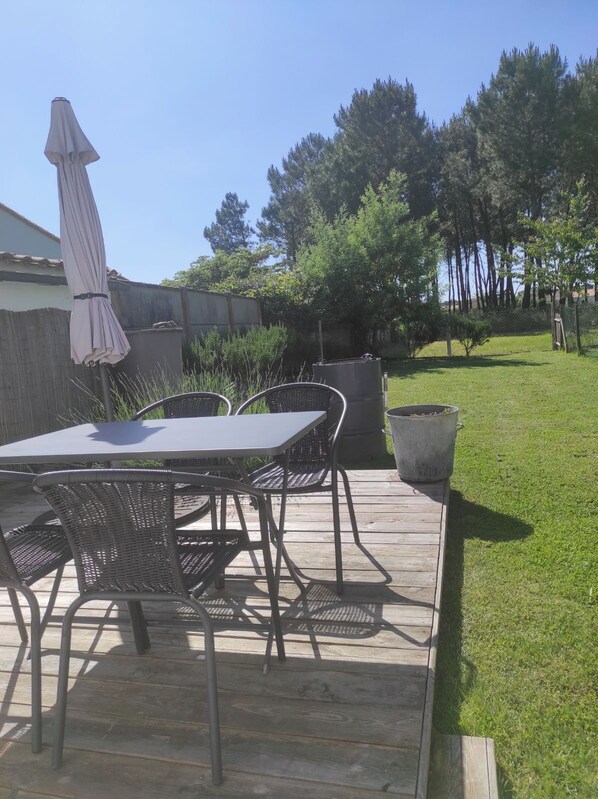 Une terrasse avec une table et des chaises, une poubelle et un réservoir d’eau.