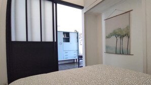 A bedroom with a patterned bedspread, a wardrobe, and a painting of trees on the wall. - House with land LES MATHES/LA PALMYRE (Les Mathes)