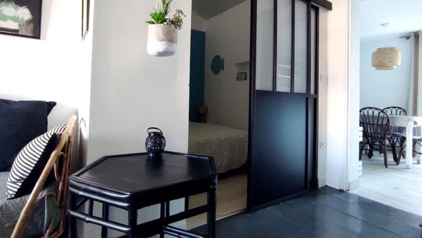 A room with a sliding door leading to a dining area, a small table with a decorative item, and a hanging plant. - House with land LES MATHES/LA PALMYRE (Les Mathes)