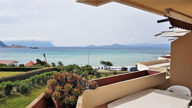 A balcony with a view of the sea, a distant ship, and a mountainous landscape. - Terza Spiaggia la Filasca (Golfo Aranci)