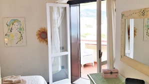 A room with a bed, a dresser, a mirror, and a door leading outside. - Terza Spiaggia la Filasca (Golfo Aranci)
