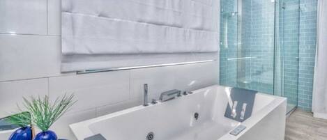 A modern bathroom with a large bathtub, a glass shower enclosure, and a towel rack.