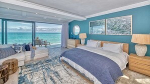 A bedroom with a large bed, a sofa, and a view of the sea. - Marlin Manor (Struisbaai)