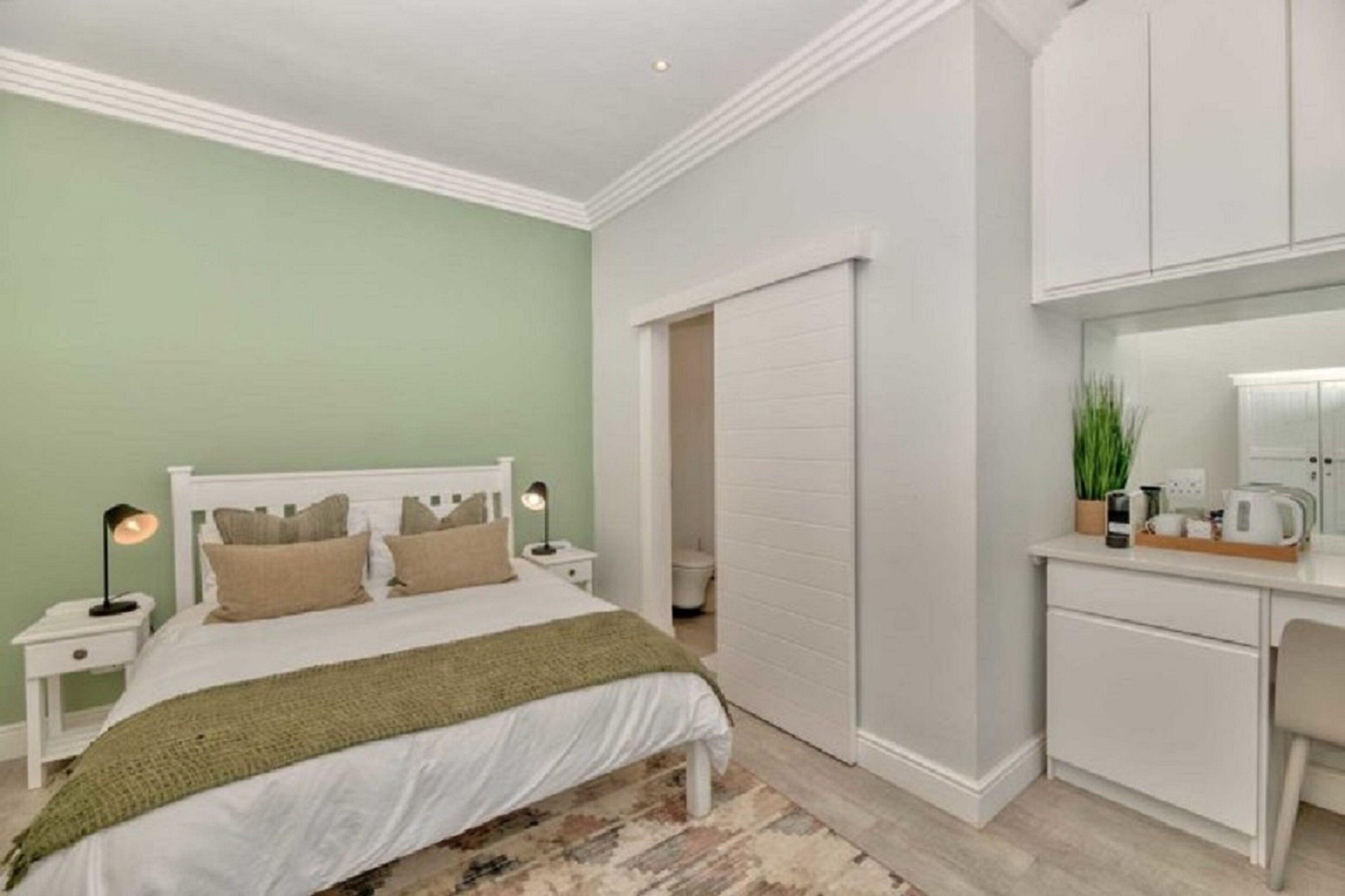 Un dormitorio con cama, mesitas de noche, escritorio y armario.