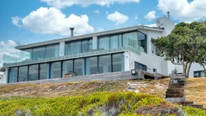 A modern house with large glass windows, a flat roof, and a satellite dish. - Marlin Manor (Struisbaai)