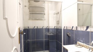 Een badkamer met een douchecabine van glas, een wastafel met spiegel, en een toilet.