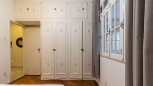 Un dormitorio con cama, armario y ventana con cortinas.