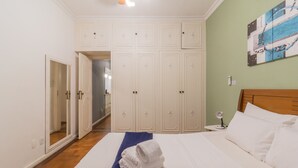 Una camera d'albergo con un letto, un asciugamano blu, mobili bianchi e un quadro appeso al muro.