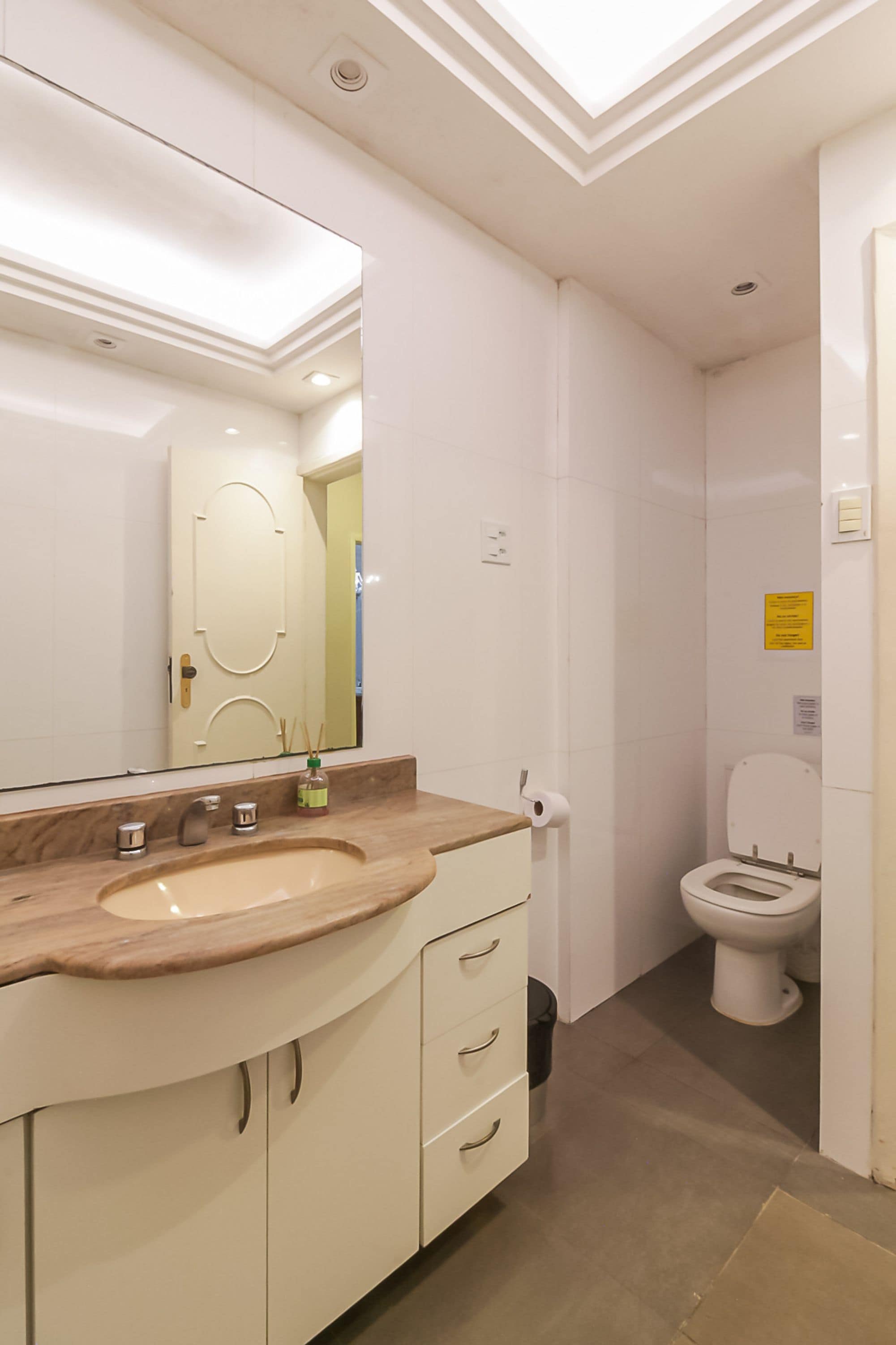 A bathroom with a white vanity, a mirror, a toilet, and a shower area.