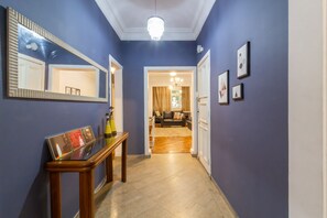 Een gang met een houten bankje, een spiegel en ingelijste foto's aan de muur.