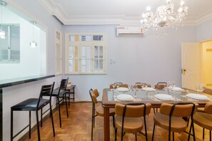 A dining area with a table set for six, surrounded by chairs, and a chandelier above.