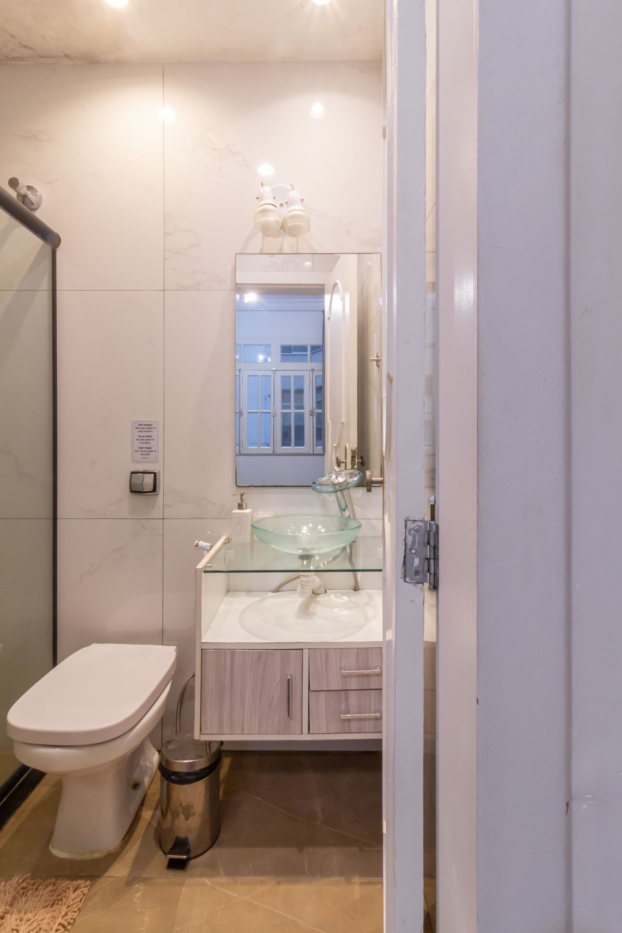 A modern bathroom with a glass sink, white toilet, and a mirror above the sink.