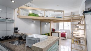 A modern kitchen with a built-in microwave, a sink, and a wooden loft bed with a green blanket. - 1 Minute From Copacabana Beach A923 (Rio de Janeiro)