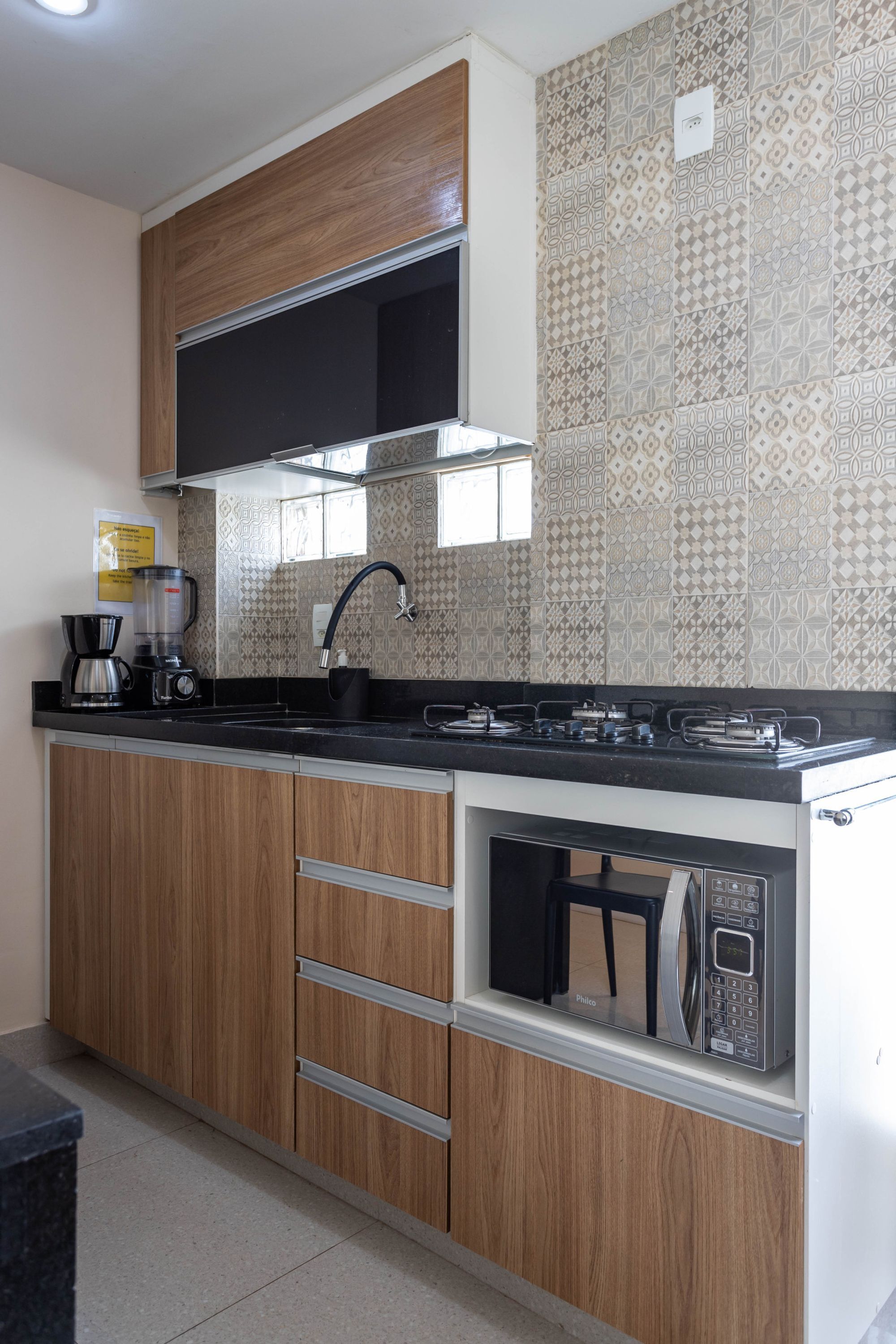 Una cocina moderna con armarios de madera, encimera negra, microondas integrado y cocina a gas.