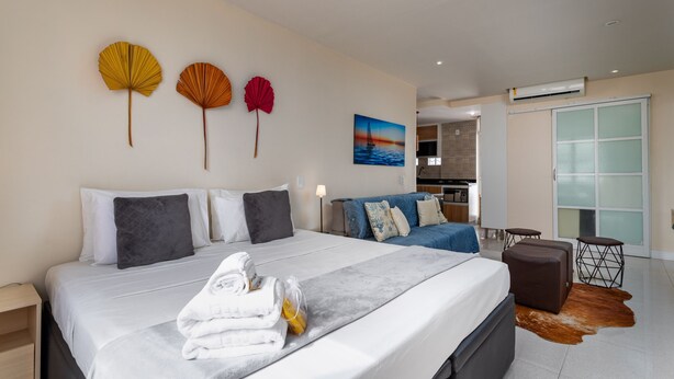 A modern hotel room with a large bed, a sofa, and a dining area.
