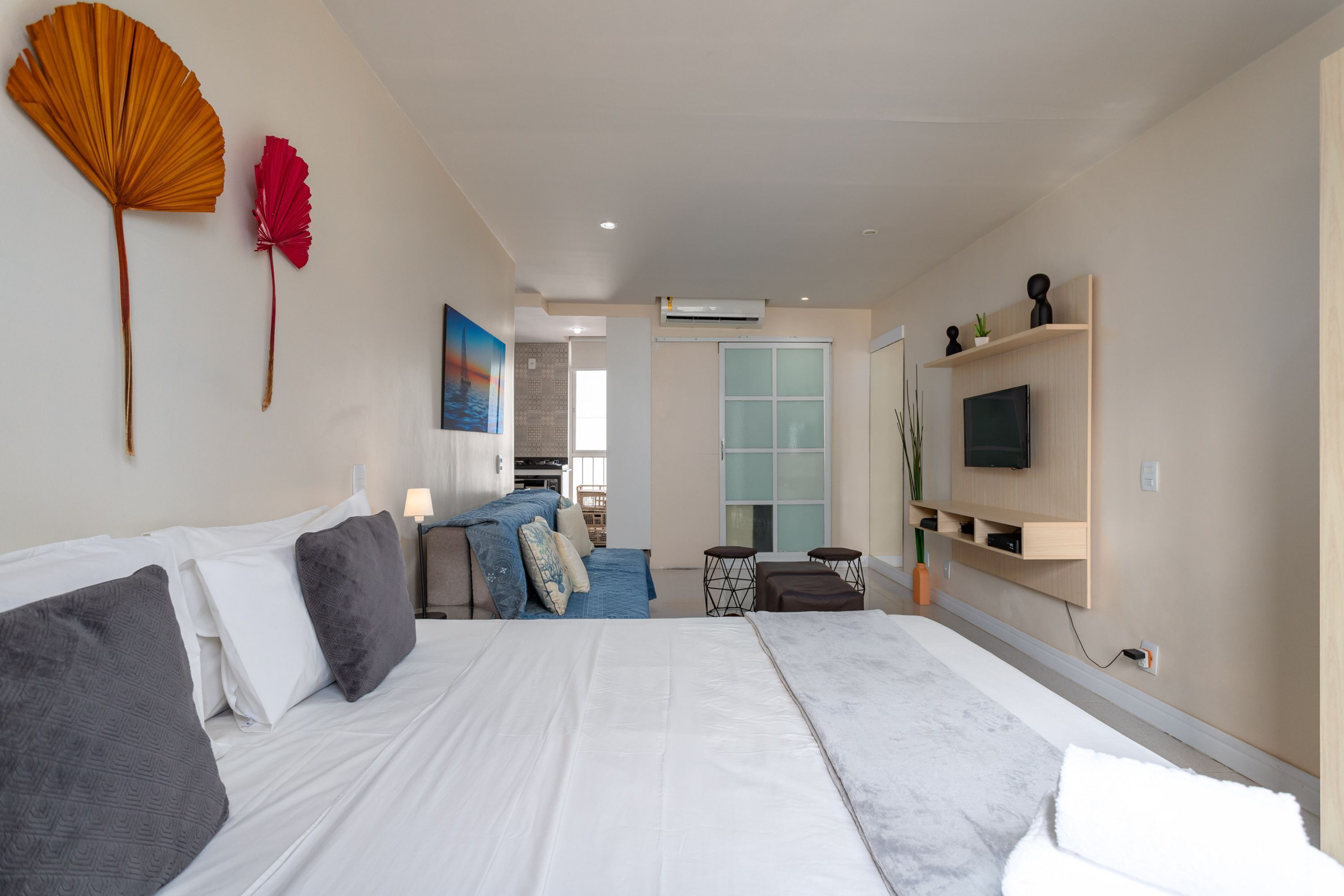 Habitación de hotel moderna con una cama grande, televisión y zona de estar con vista a la ciudad.