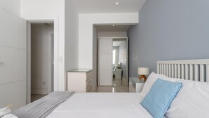 A modern bedroom with a bed, bedside table, and a mirror.