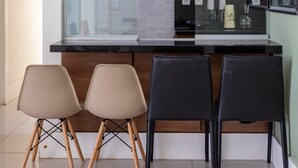 A modern office space with a glass partition, a black countertop, and three chairs.