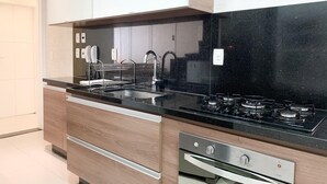 A modern kitchen with a black countertop, stainless steel appliances, and wooden cabinets.