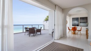 A modern hotel room with a balcony overlooking the sea, furnished with wicker chairs and a dining table. - Penthouse With sea View on the Beachfront Vsc1 (Rio de Janeiro)