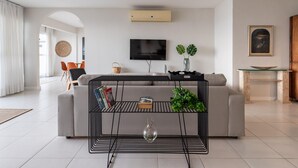 A modern living room with a sofa, a coffee table, and a TV mounted on the wall. - Penthouse With sea View on the Beachfront Vsc1 (Rio de Janeiro)