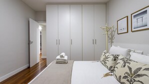 A bedroom with a large wardrobe, a bed with floral bedding, and a coat rack. - Penthouse With sea View on the Beachfront Vsc1 (Rio de Janeiro)