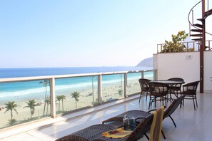 A balcony with a view of the beach and ocean. There are wicker chairs and a table with a bottle and a glass. - Penthouse With sea View on the Beachfront Vsc1 (Rio de Janeiro)