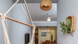 A room with a hanging hammock, a colorful checkered rug, a dining area with a table and chairs, and a wall-mounted plant. - Copacabana Ideal for Couples Rpp913 (Rio de Janeiro)