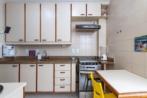 A compact kitchen with white cabinets, a gas stove, a coffee maker, and a blender.