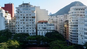 Un hotel con varios pisos, un llamativo letrero que dice 'HOTEL' y montañas al fondo.