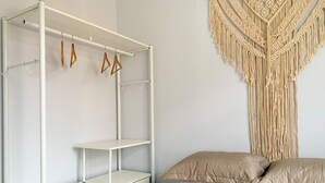 A bedroom with a white metal bed frame, a macrame wall hanging, and a bed with beige bedding. - 6 Minutes From Copacabana Beach Br1033 (Rio de Janeiro)