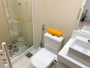 A bathroom with a glass-enclosed shower, a toilet with a yellow towel on top, a bidet, and a sink. - 6 Minutes From Copacabana Beach Br1033 (Rio de Janeiro)