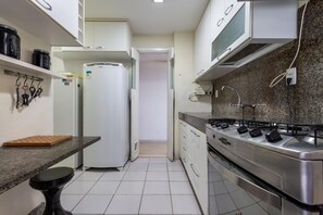 A kitchen with white cabinets, a stainless steel stove, a white refrigerator, and a countertop with a cutting board. - Attractive in Barra da Tijuca With a View As1602 (Rio de Janeiro)