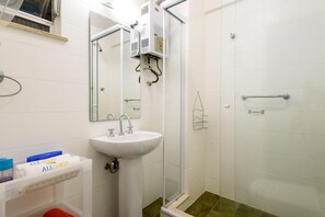 Un bagno con lavandino bianco, specchio e cabina doccia in vetro.