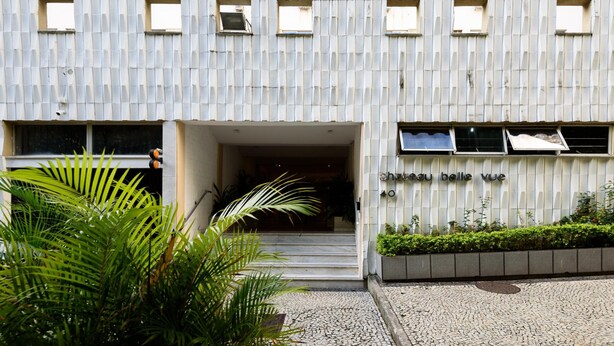 Ein Gebäude mit einer Wellmetallfassade, eine Treppe, die zu einem Eingang führt, und ein Schild mit der Aufschrift "chaou belle vue".