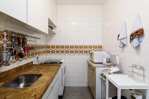 Una cucina compatta con piano di lavoro in granito, un lavandino, un forno a microonde, una macchina da caffè e un portasciutto.