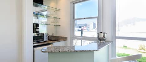 A modern kitchen with a granite countertop, a built-in microwave, and a coffee maker.