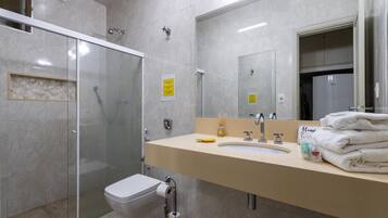 A modern bathroom with a glass-enclosed shower, a toilet, a sink with a mirror, and a towel rack.